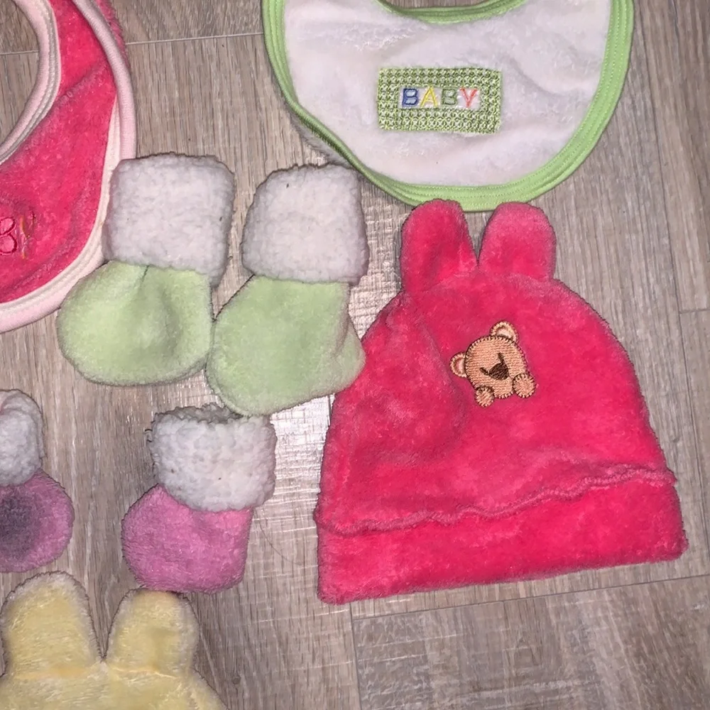 Colorful bundle of plush baby bibs, hats, and mittens